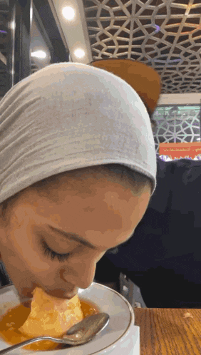 a woman in a white head scarf is eating food from a plate