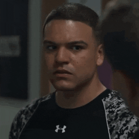 a man is wearing a black under armour shirt and a camouflage jacket .