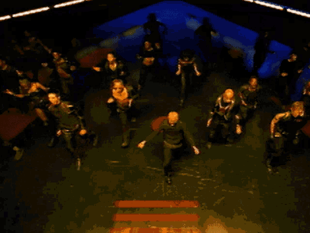 a group of people are dancing in a dark room with a blue background