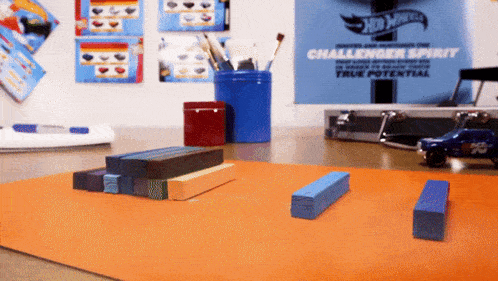a hot wheels challenger spirit poster hangs on a wall above a table