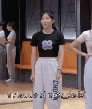 a girl in a black crop top and white pants is standing in a room