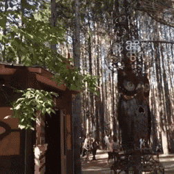 a group of people are walking through a forest with a sculpture in the foreground that looks like a bear