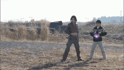 two men standing in a field with one holding a purple object in his hand
