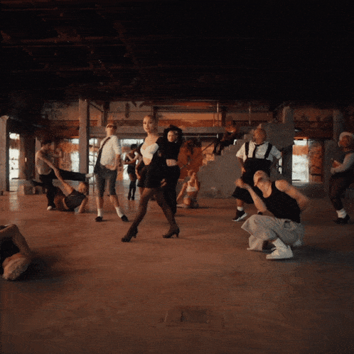 a group of people are dancing in a dark room and one of them is kneeling down