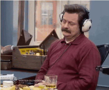 a man with a mustache wearing headphones is sitting at a table with a glass of beer .