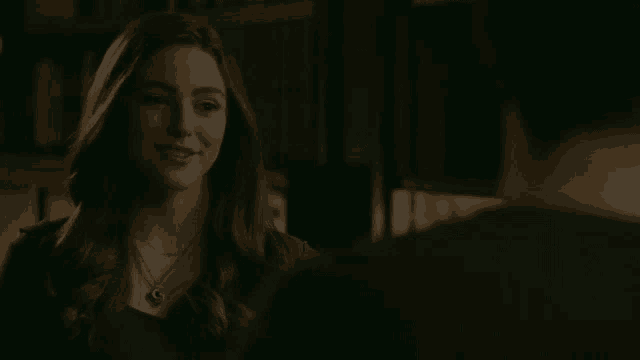 a woman wearing a necklace is smiling while looking at a man