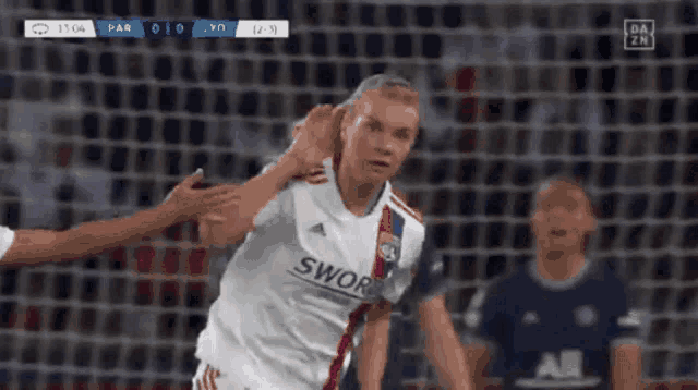 a soccer player wearing a sworn jersey is being hugged