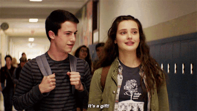 a boy and a girl are walking down a hallway with the girl saying it 's a gift