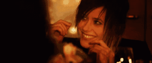 a woman is smiling while holding a glass of wine in her hand .