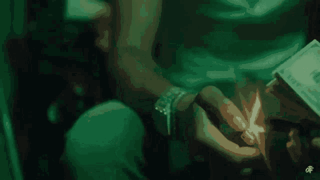 a person is lighting a match in their hand while holding a stack of money .