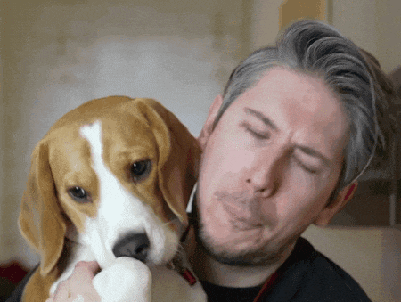 a man with his eyes closed is holding a beagle
