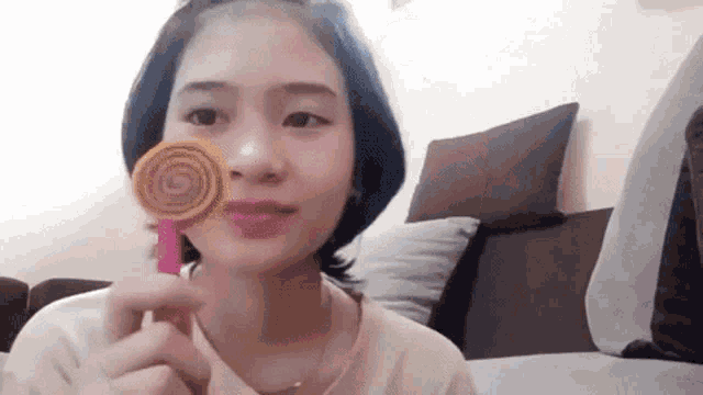 a woman is holding a pink lollipop in front of her face .