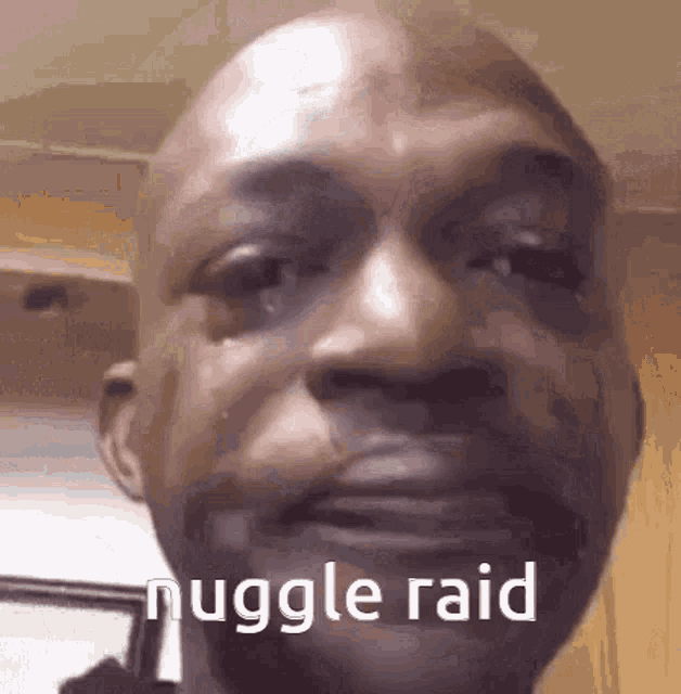 a close up of a bald man 's face with the words nuggle raid written on it .