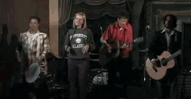 a group of people are standing on a stage playing instruments .