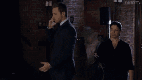 a man in a suit and tie stands next to a woman holding a bird in a dark room with the hashtag #youngertv