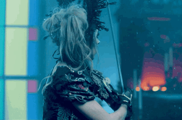 a woman holding a sword in front of a colorful window