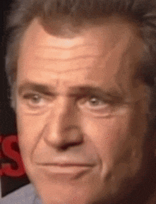 a close up of a man 's face with a red s on the bottom left