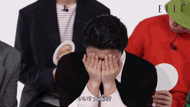 a man covering his face with his hands in front of a magazine called elle