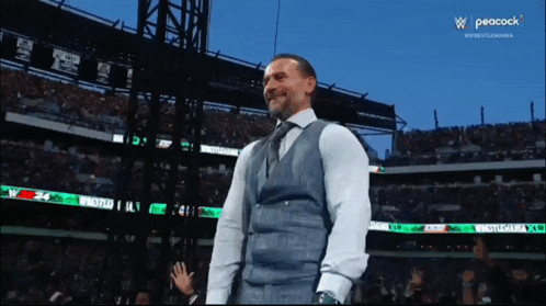 a man in a suit and tie is standing in front of a stadium with peacock on the screen