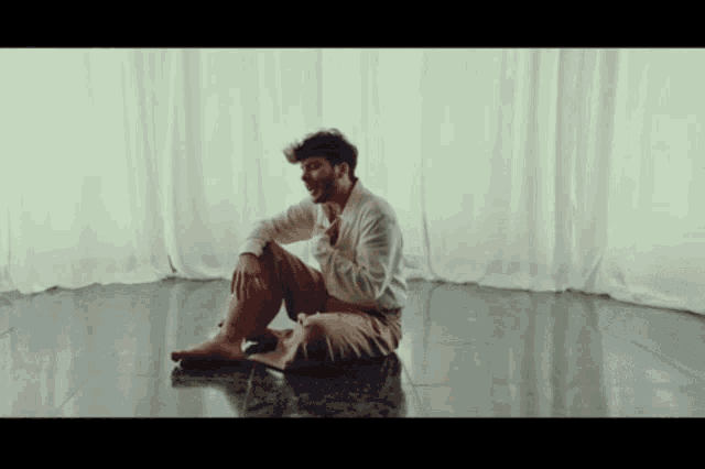 a man sits on the floor in front of a window