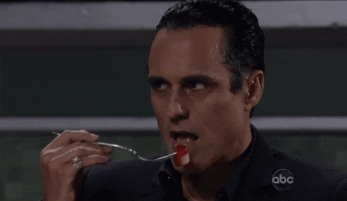 a man is eating something with a fork and the abc logo can be seen in the background