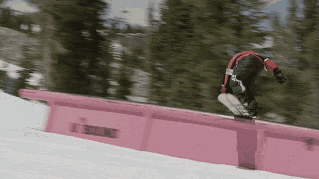 a snowboarder is doing a trick on a pink railing that says l.t. snowboarding on it