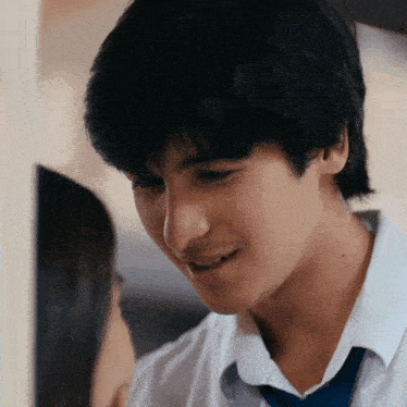 a young man in a white shirt and blue tie is looking at a young woman .
