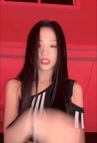 a woman with long black hair is wearing a black and white adidas shirt