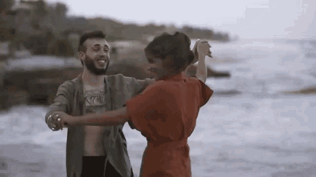 a man and a woman are dancing on a beach .