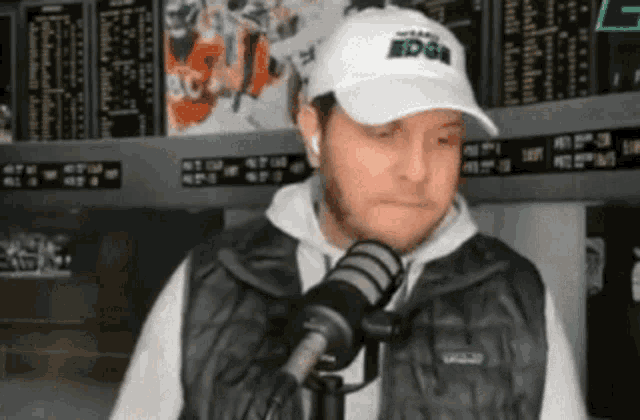 a man wearing a white hat with the word edge on it is talking into a microphone