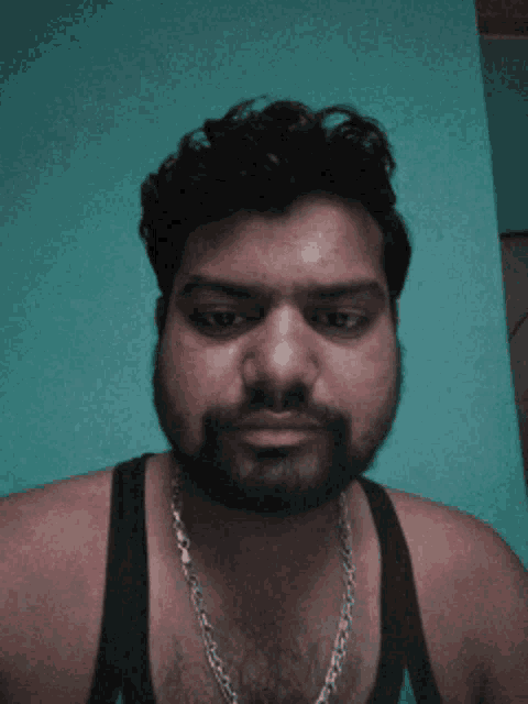 a man with a beard wearing a tank top and a chain around his neck
