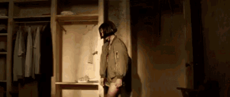 a woman is standing in a dark room in a closet .