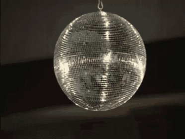 a disco ball hanging from the ceiling with a reflection of a person in it