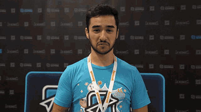 a man wearing a blue shirt with a lanyard around his neck that says xcon on it