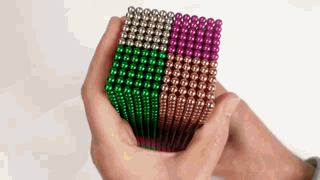 a person is holding a cube of magnet beads