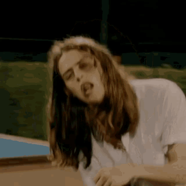 a woman with long hair and a black eye is wearing a white t-shirt .
