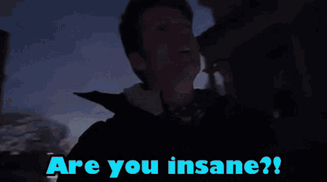 a man in headphones is standing in front of a building with the words " are you insane " written above him
