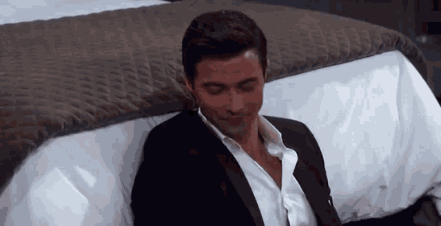 a man in a suit and tie is laying on a bed .