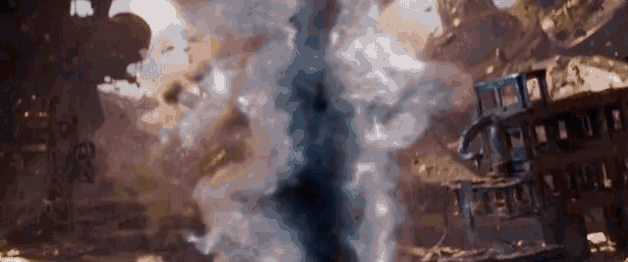 a large explosion is taking place in the middle of a city with a lot of smoke coming out of it .