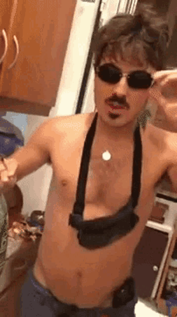 a shirtless man wearing sunglasses and a necklace