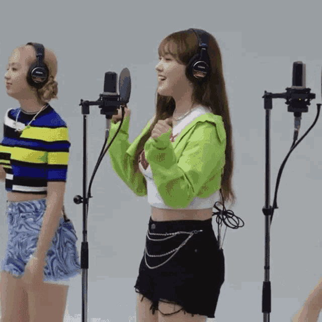 a woman in a green sweater is singing into a microphone while wearing headphones .
