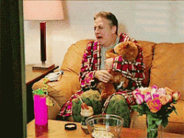 a man in a plaid robe is sitting on a couch with a teddy bear