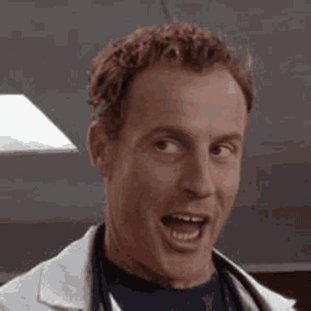 a man in a lab coat is smiling with his eyes closed and his mouth open .