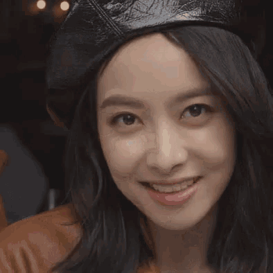 a close up of a woman wearing a beret making a heart shape with her finger .