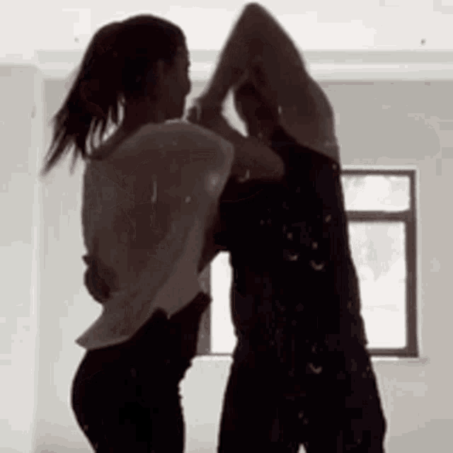 a man and a woman are dancing in a room with a window in the background .