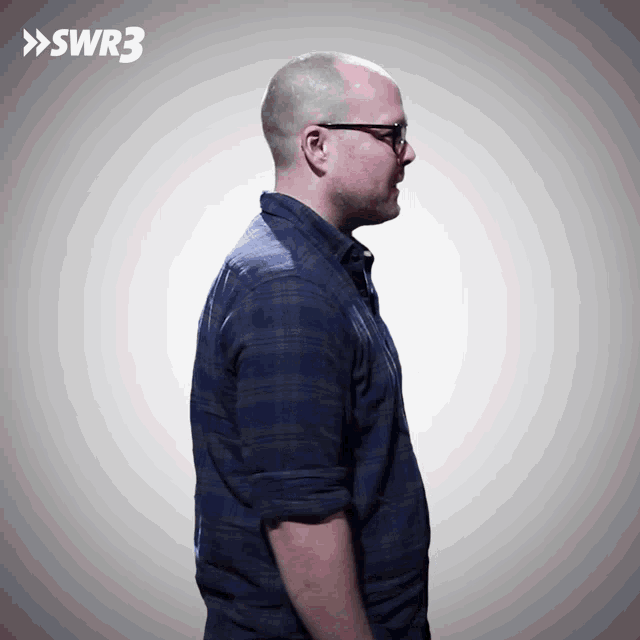 a man wearing glasses and a plaid shirt is standing in front of a sign that says swr3