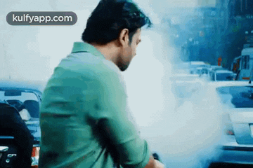 a man is sitting in front of a car with smoke coming out of the engine .