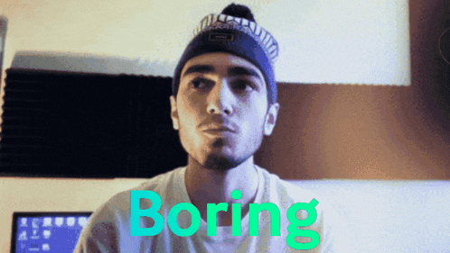 a man wearing a beanie and a t-shirt with the word boring in green