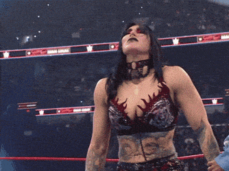 a woman in a wrestling ring holds a championship belt in her hands
