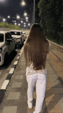 a woman walking down a sidewalk wearing a shirt that says milwaukee on the back